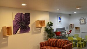 A room with a striped sofa, a wooden table, and a large purple flower painting on the wall. - Cozy studio, mountain view (Montgenèvre)