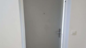 A closed door with a handle, a light switch, and a small hole above the handle. - Apartment sea view, AC - 4 guests (Lumio)