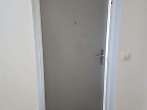 A closed door with a handle, a light switch, and a small hole above the handle. - Apartment sea view, AC - 4 guests (Lumio)