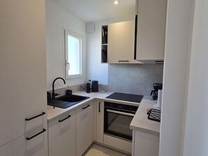 A modern kitchen with a built-in oven, a sink, and a window. - Apartment sea view, AC - 4 guests (Lumio)
