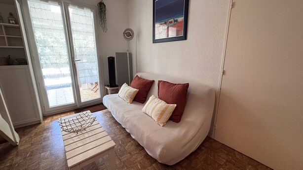 Ein Wohnzimmer mit einer Couch, einem kleinen Tisch, einem Fernseher und einer Tür.