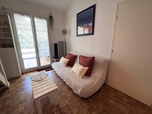 A living room with a sofa, a small table, a TV, and a door. - House with parking - 5 guests (Saint-Cyprien)