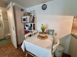 A dining area with a table, chairs, a clock, and a shelf with kitchen appliances. - House with parking - 5 guests (Saint-Cyprien)