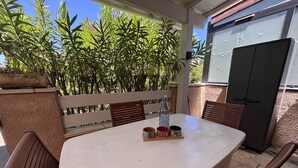 Eine Terrasse im Freien mit Tisch, Stühlen, einer Flasche und Bechern.