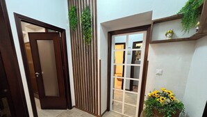Un corridoio con pavimento in legno, una porta scorrevole, un giardino verticale e un vaso con girasoli.