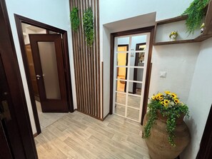A hallway with a wooden floor, a sliding door, a vertical garden, and a potted plant with sunflowers. - Teresa's Holiday Home | Your Gateway to Western Sicily with private parking (Salemi)