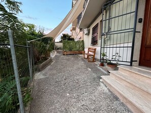 A narrow alleyway with a concrete path, a wooden bench, and potted plants. - Teresa's Holiday Home | Your Gateway to Western Sicily with private parking (Salemi)