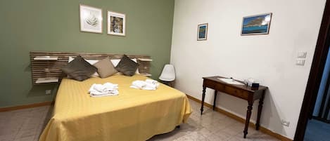 Una habitación de hotel con cama, mesita de noche y una lámpara de pared.