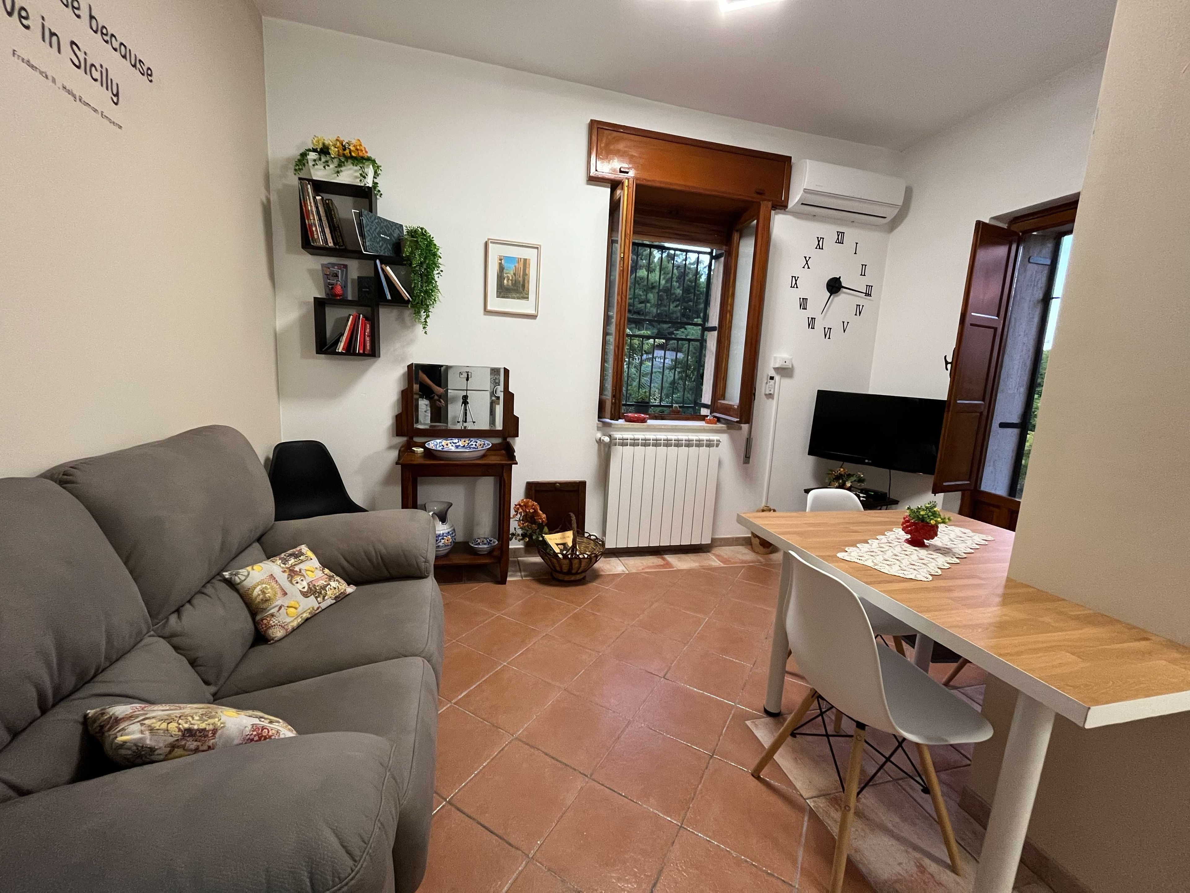Un espacio habitable pequeño con un sofá, una mesita, un televisor y un reloj en la pared.