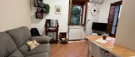 Un espacio habitable pequeño con un sofá, una mesita, un televisor y un reloj en la pared.