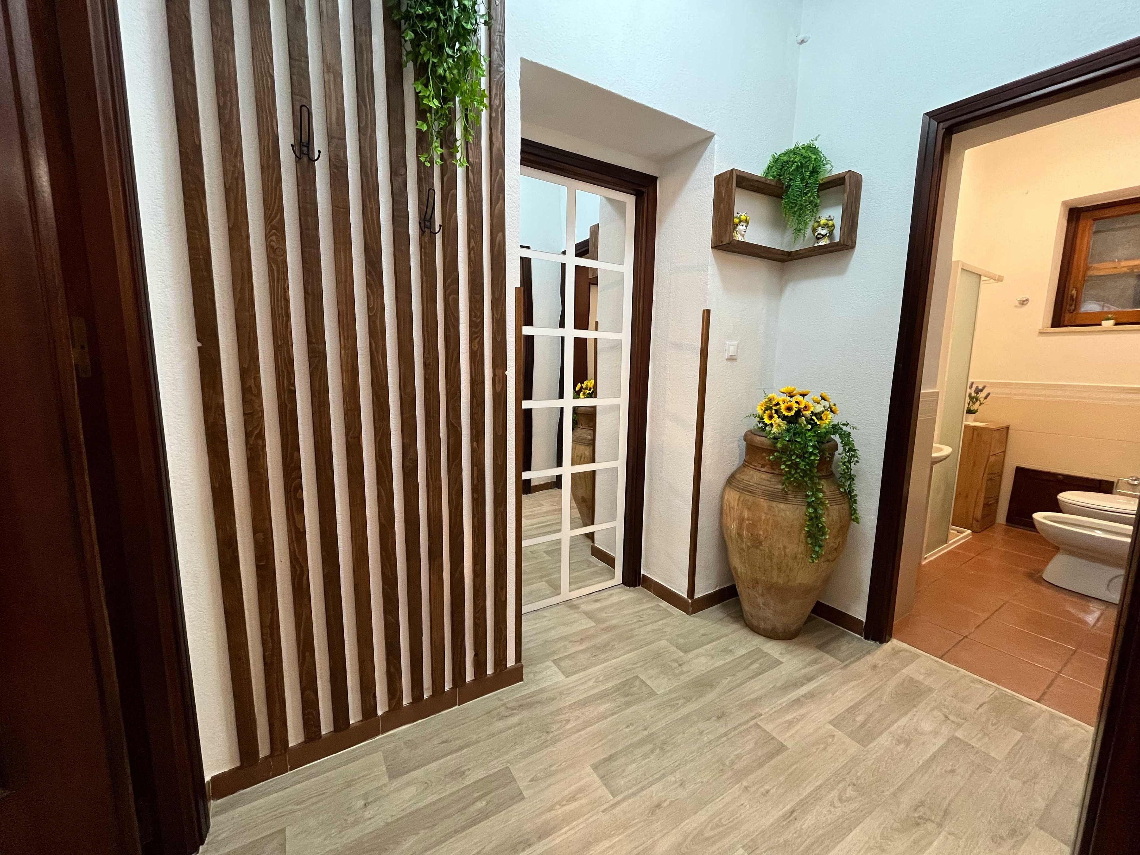 Ein Flur mit einer Trennwand aus Holzlatten, einem Blumentopf und einer Tür zu einem Badezimmer.