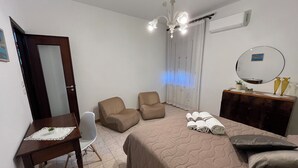 Una camera da letto con un letto, due poltrone, una scrivania, una cassettiera e un lampadario.