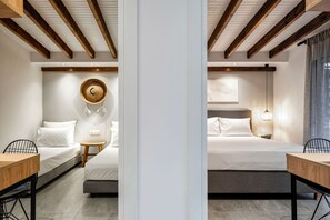 Ein Hotelzimmer mit zwei Betten, einem kleinen Tisch, einem Sessel, einem Wandteppich und einer Decke mit Holzbalken.