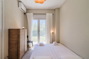 Ein Schlafzimmer mit einem Bett, einem Nachttisch, einem Kleiderschrank und Blick durch eine Glastür.