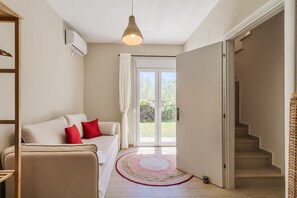 Ein modernes Wohnzimmer mit einer Couch, einem roten Teppich, einer Treppe und einem großen Fenster.