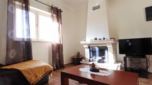 A living room with a fireplace, a television, and a sofa. - MyStay - Casa do Carmo (Alvite)