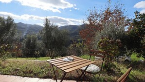 A wooden table with a cushion and a bench in a garden with a mountain view. - MyStay - Casa do Carmo (Alvite)