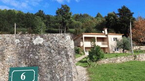 A two-story building with a balcony, a stone wall with a number sign, and a pathway leading to the building. - MyStay - Casa do Carmo (Alvite)