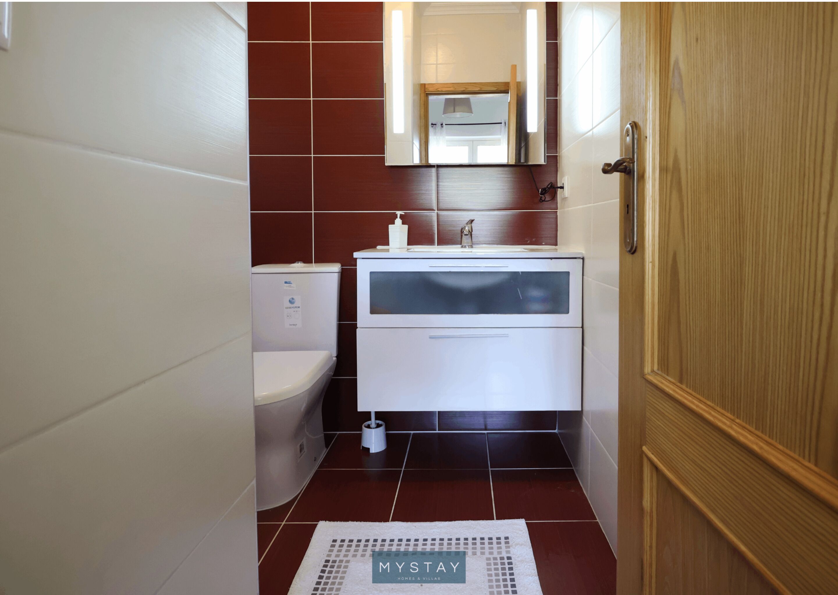 Ein kleines Badezimmer mit Toilette, Waschbecken und Spiegel.