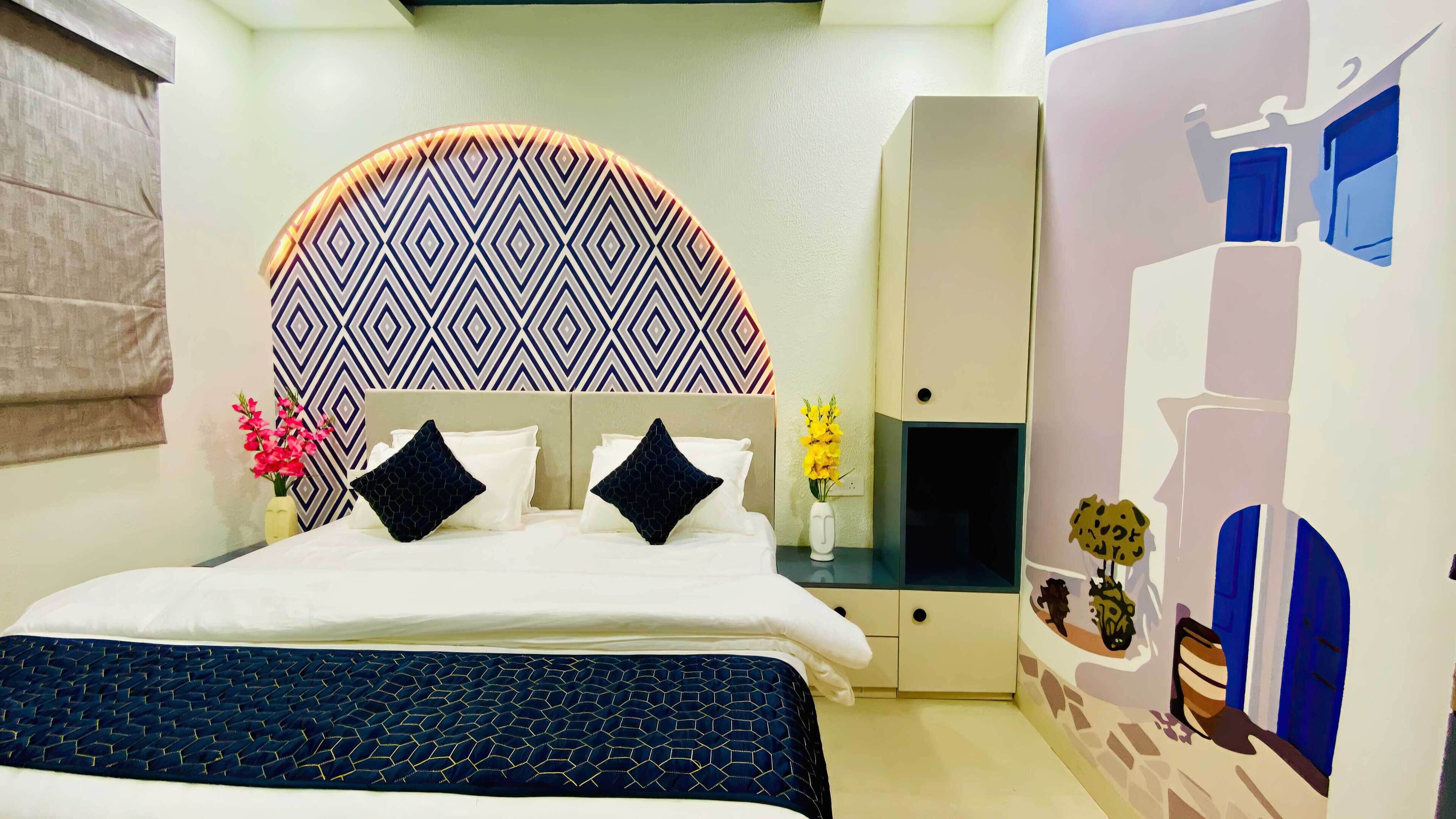 Habitación de hotel con cama, mesita de noche, armario, un diseño decorativo en la pared y ventana con cortinas.
