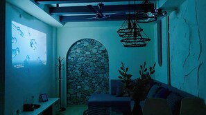 A room with a stone wall arch, a sofa, a coat rack, and a ceiling fan. - Global Village BnB (Indore)