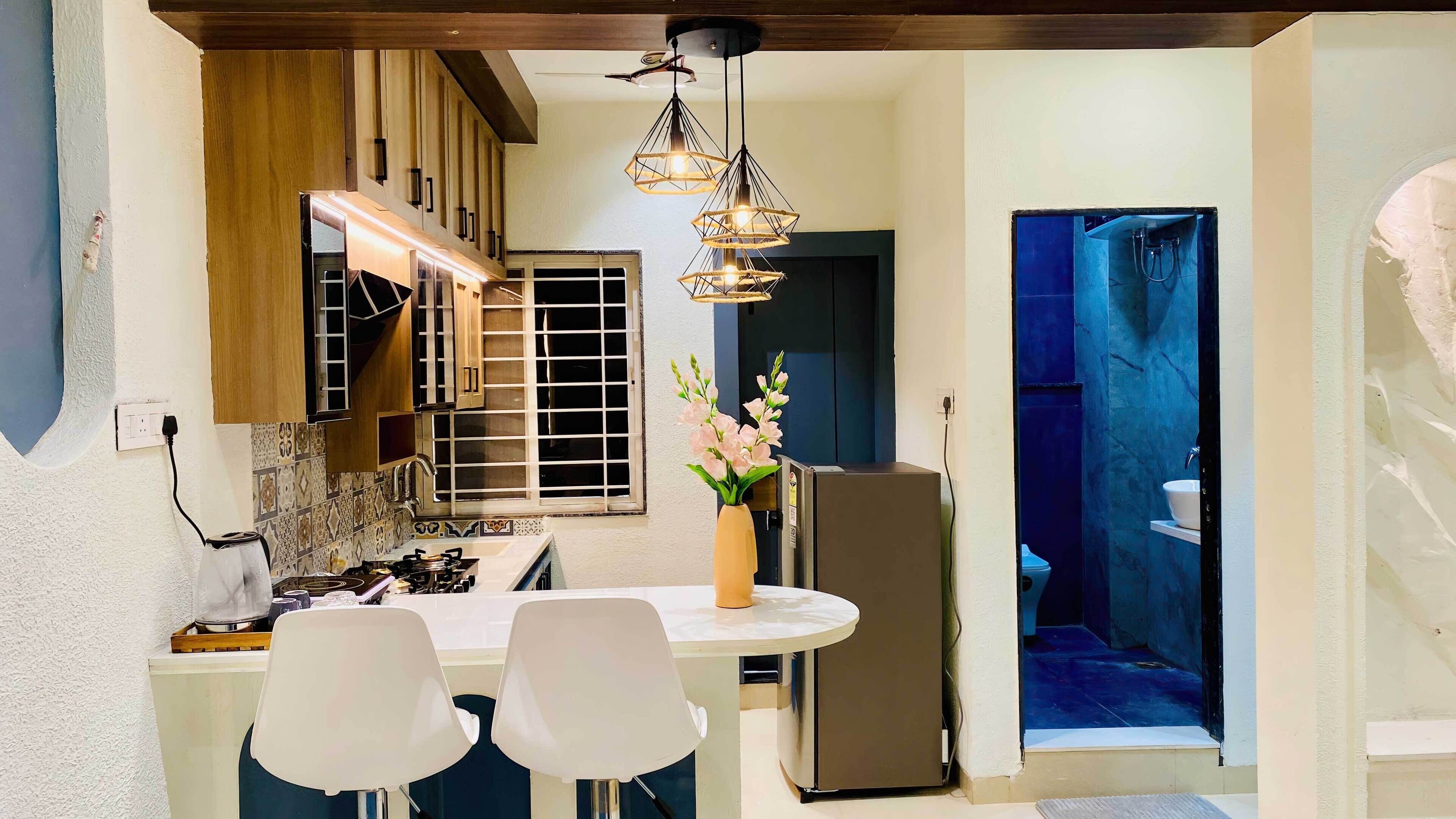 Cocina compacta con comedor, refrigerador y lavamanos.