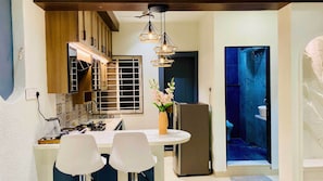 A compact kitchen with a dining area, a refrigerator, and a sink. - Global Village BnB (Indore)