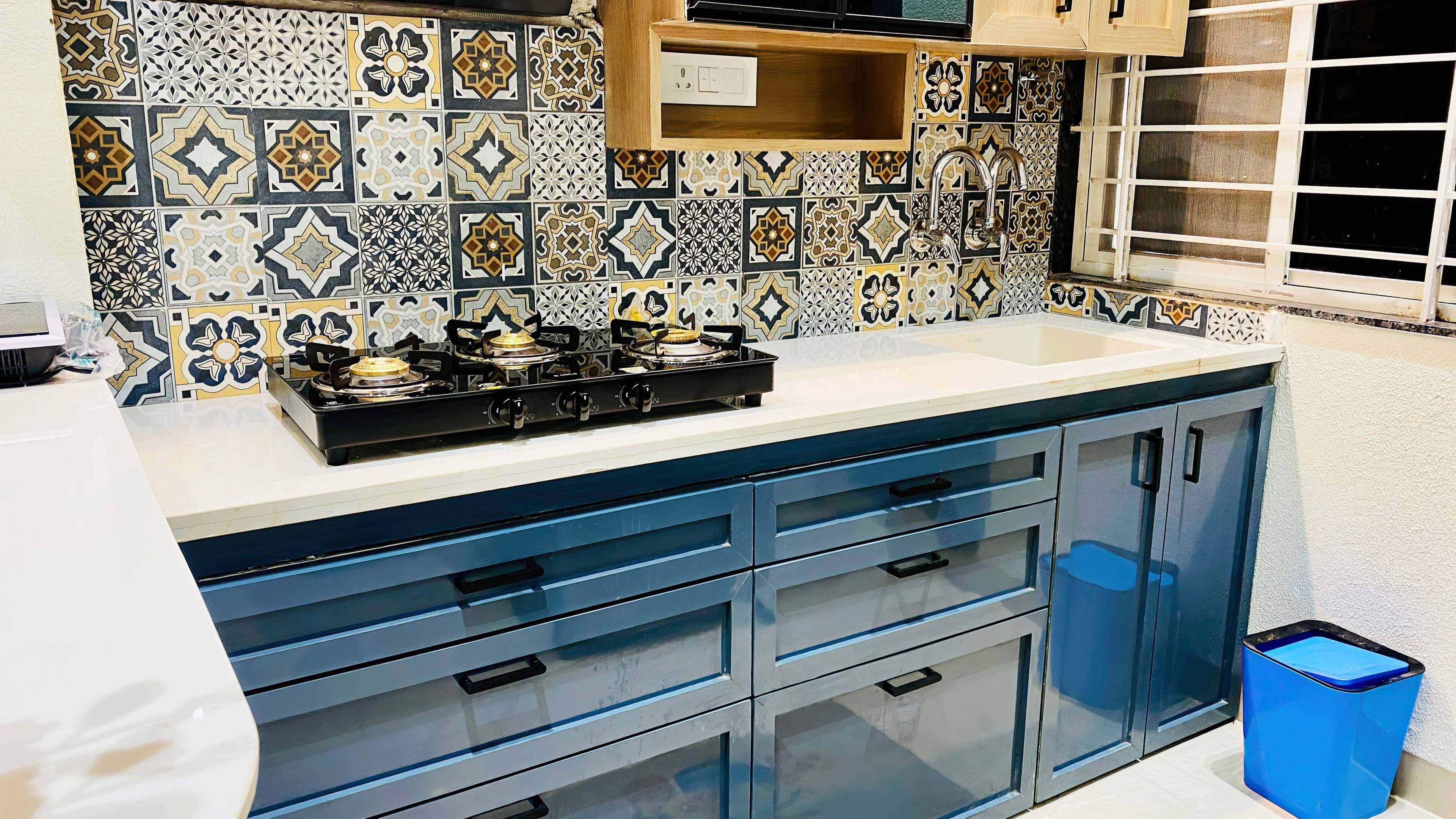 Una cucina con piano cottura a gas, mobili azzurri e piastrelle decorate.
