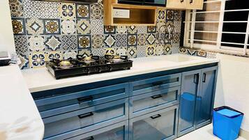 Una cucina con piano cottura a gas, mobili azzurri e piastrelle decorate.