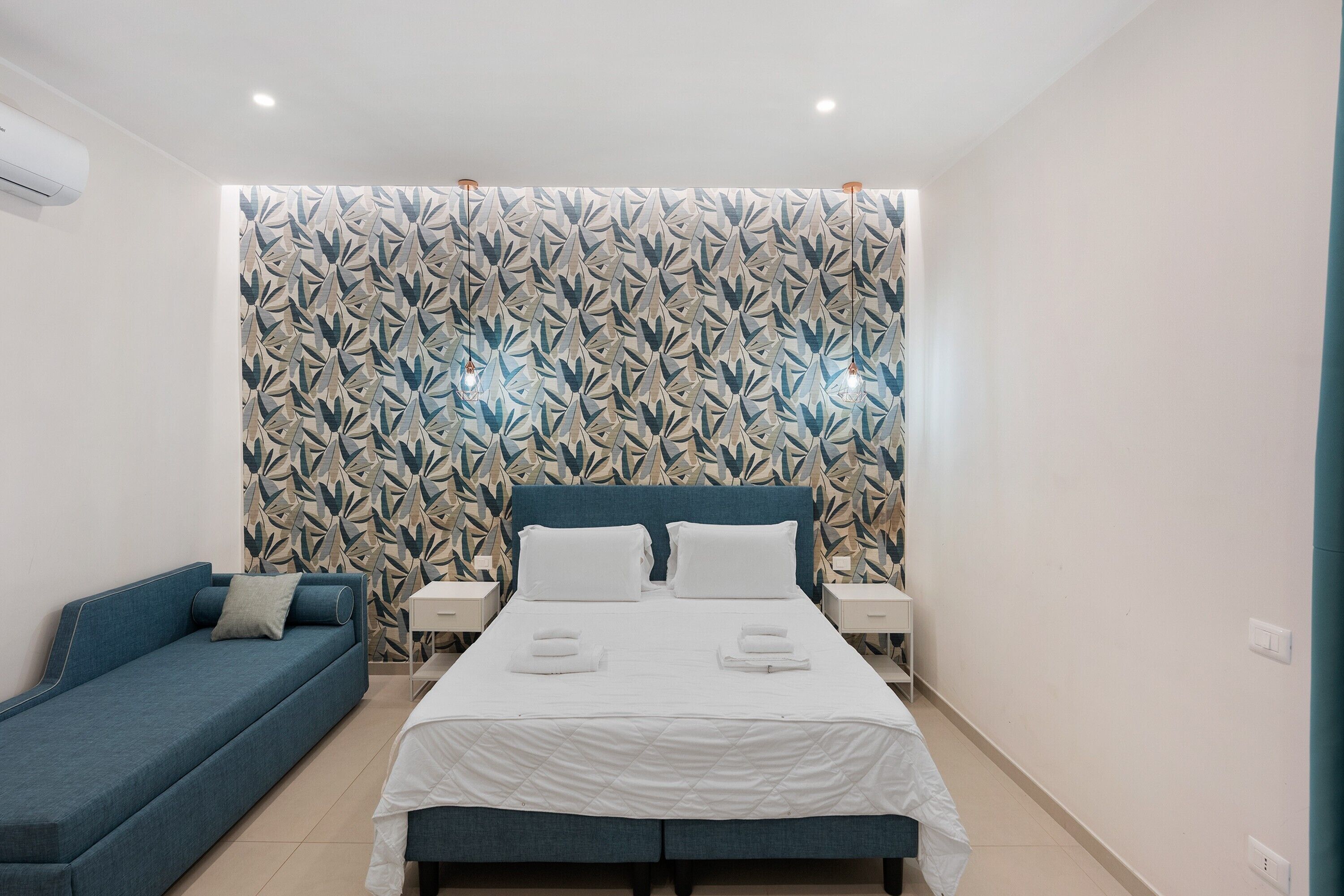 Ein Schlafzimmer mit einem Bett, einem blauen Sofa und einer Wand mit Muster.