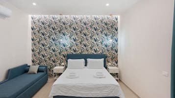 A bedroom with a bed, a blue sofa, and a patterned wall.