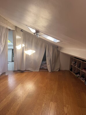 A room with a sloped ceiling, wooden flooring, and a skylight. - Charming 2-bedroom apartment with AC in Courbevoie (Courbevoie)