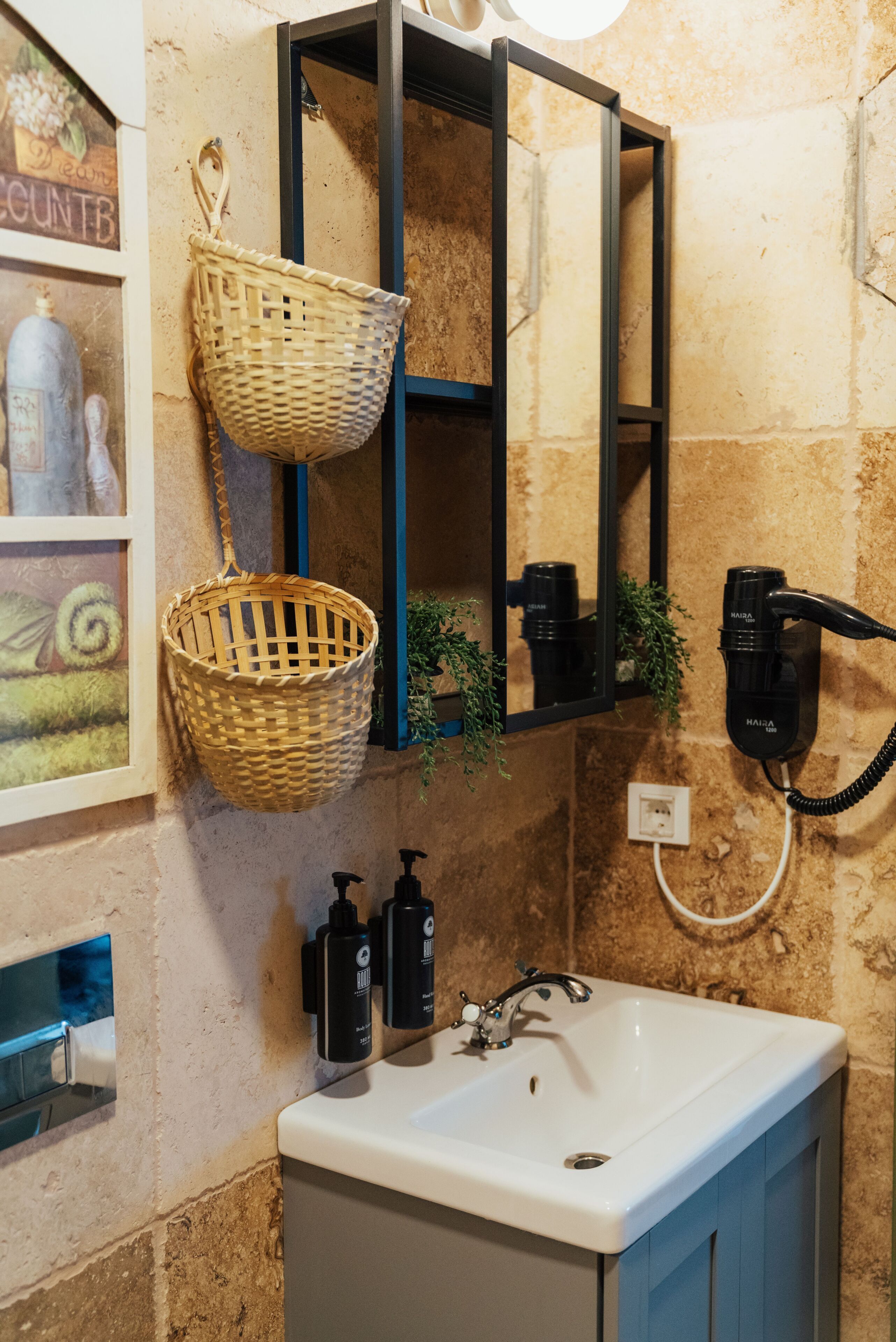 A bathroom with a white sink, a mirror, a hairdryer, and two baskets.