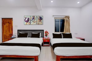 A hotel room with two beds, a wooden door, a window with curtains, and a wall-mounted artwork. - Family Rooms With Twin King bed Ravai (Calangute)