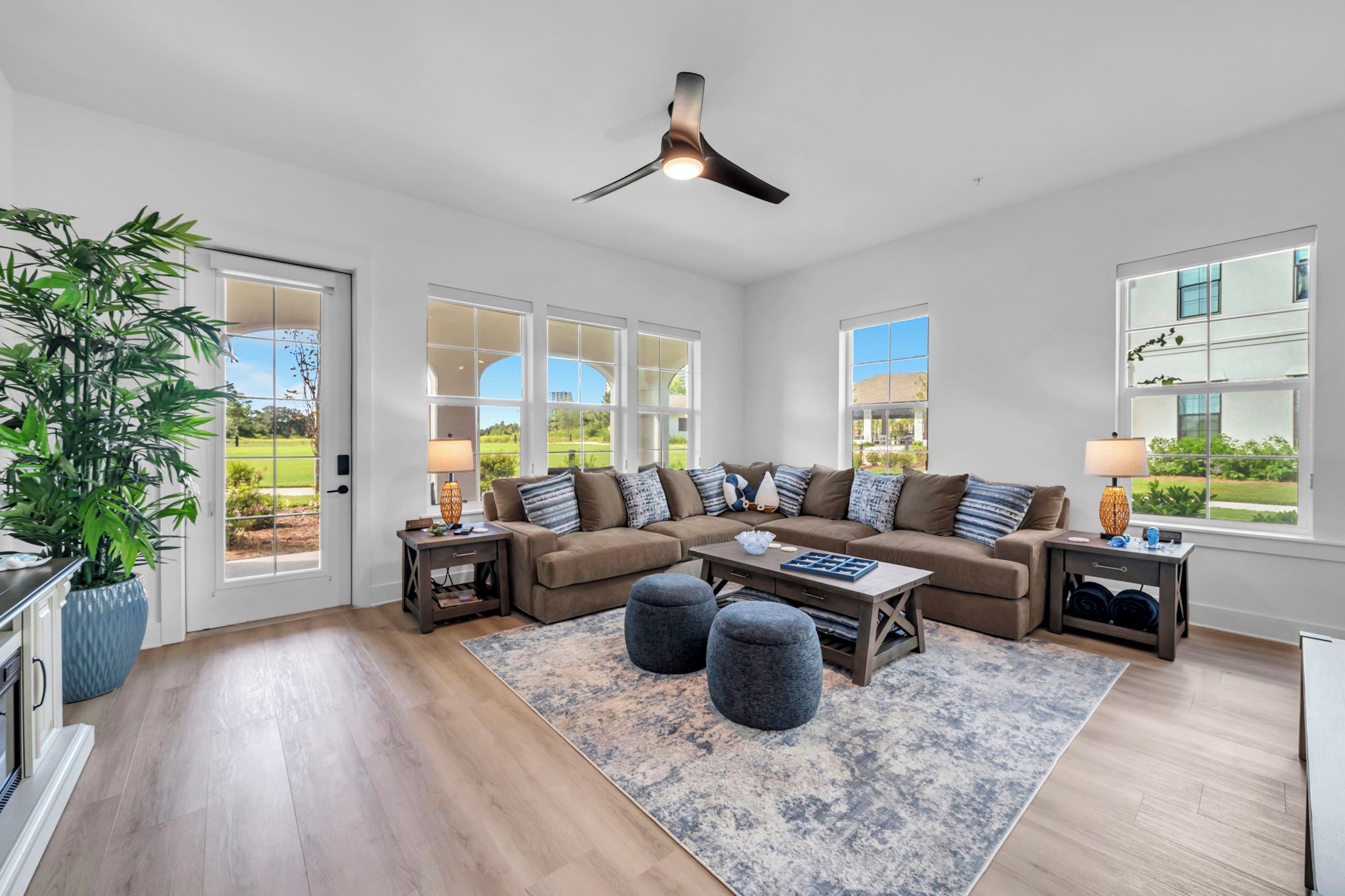 A spacious living room with a large sectional sofa, a coffee table, and a ceiling fan.