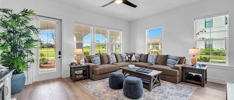 A spacious living room with a large sectional sofa, a coffee table, and a ceiling fan.
