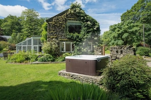 Ein Steinhaus mit Whirlpool im Garten.