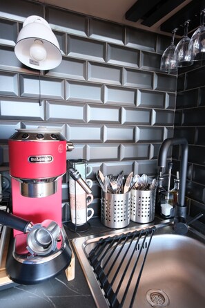 A kitchen with a red De'Longhi espresso machine, a sink, and a backsplash with a geometric tile pattern. - Arcachon centre - Studio Cabine superbe vue mer - accès plage (Arcachon)