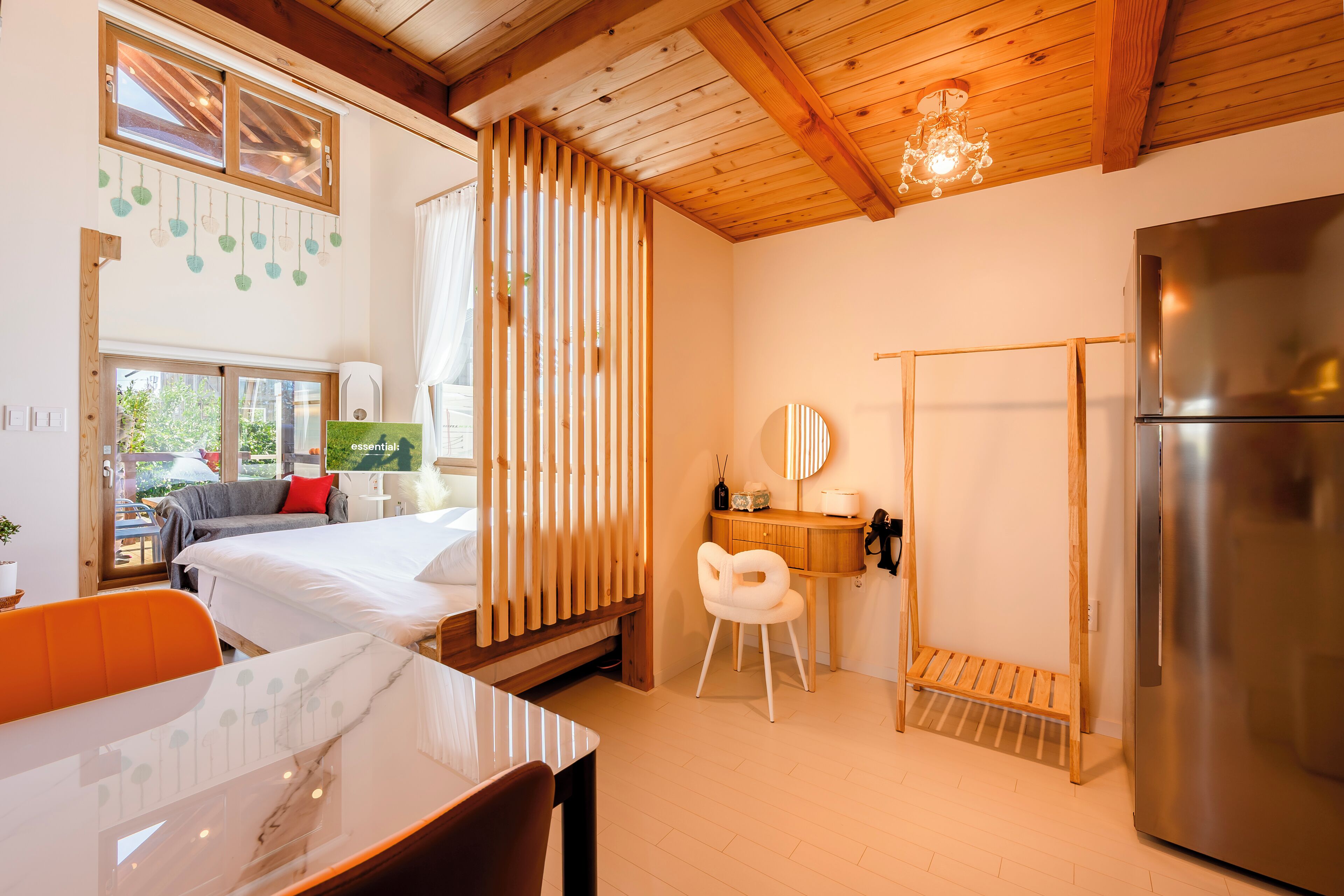 Una habitación moderna con una cama, una mesa, una silla, un refrigerador y un panel de madera.