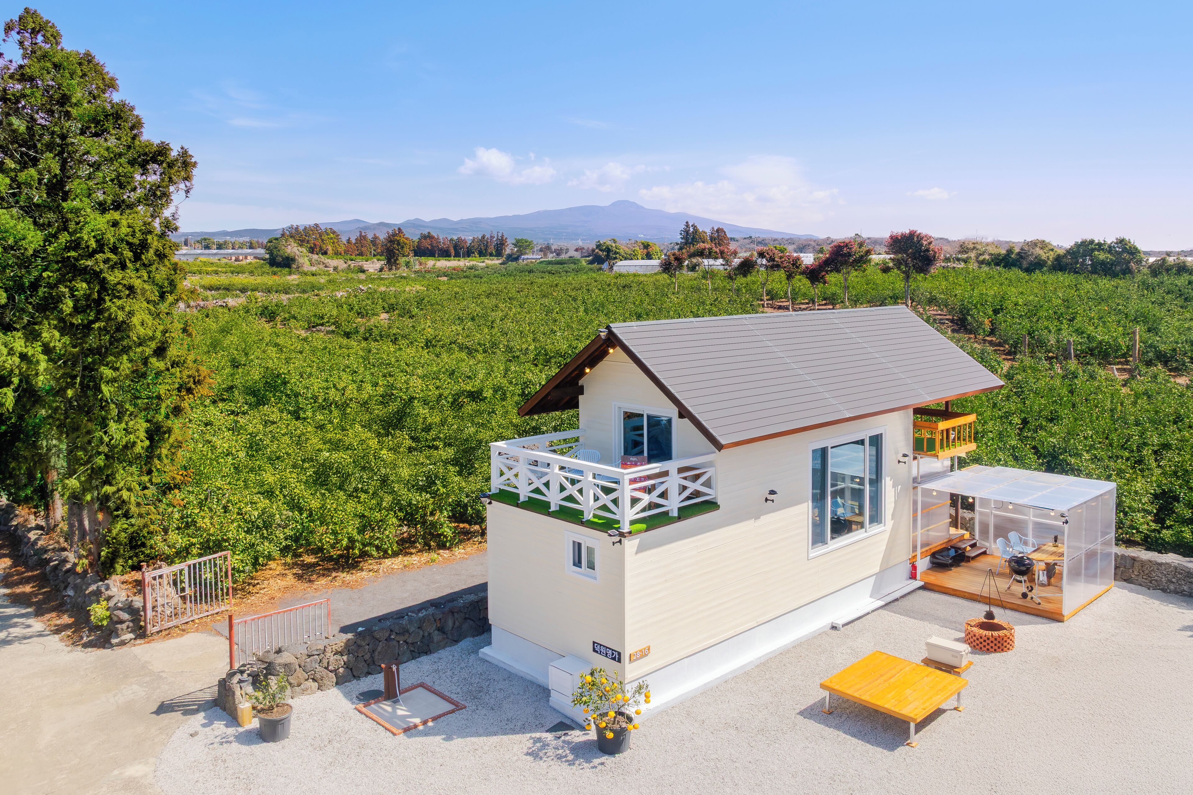 A single-story house with a balcony, a small patio area, and a view of a vineyard.