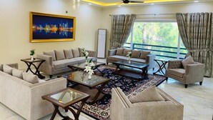 A spacious living room with a sofa set, coffee table, and a painting on the wall.
