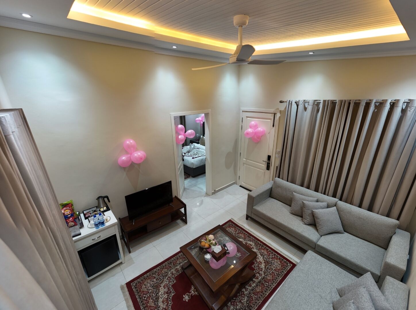 Ein Wohnzimmer mit Sofa, Couchtisch, Fernseher und Deckenventilator.