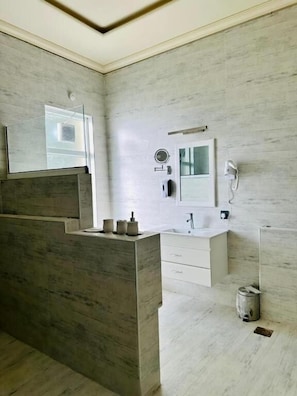 A modern bathroom with a large mirror, a sink, and a toilet. - Hidden Hills Hotel & Resort (Mansehra)