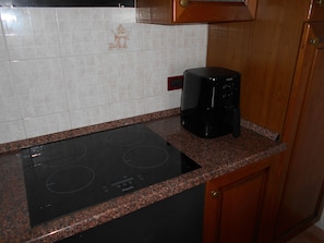 Eine Küche mit einer schwarzen Induktionskochplatte, einer Kaffeemaschine und Holzschränken.