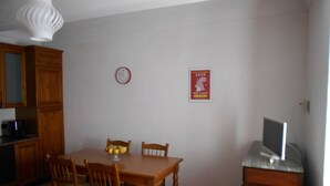 En spiseplads med et træbord, fire stole, et ur og et plakat på væggen.