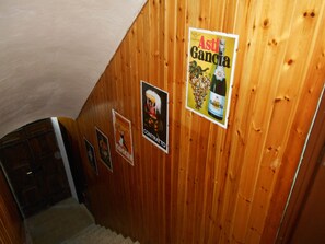 Un intérieur en bois, avec des affiches aux murs, un escalier et une porte.