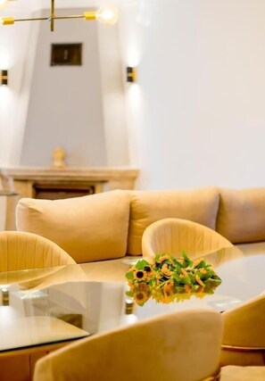 A modern dining area with a glass table, beige upholstered chairs, and a vase of flowers. - villa maria caetana (Frazão)