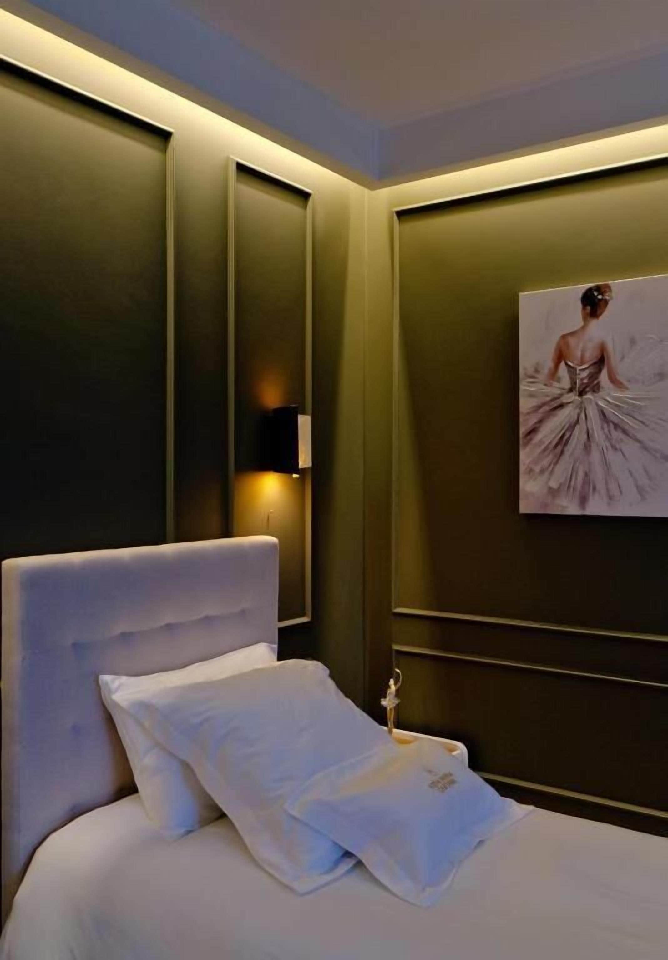 A hotel room with a large bed, a wall-mounted lamp, and a painting.