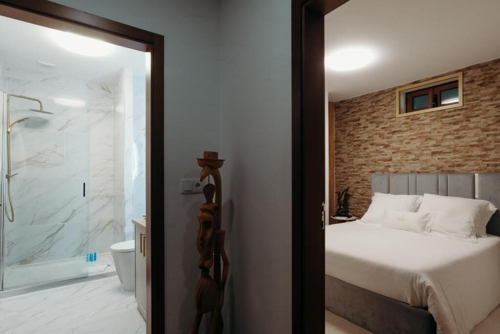 Une salle de bain avec une douche à parois de verre, des toilettes et une sculpture en bois.
