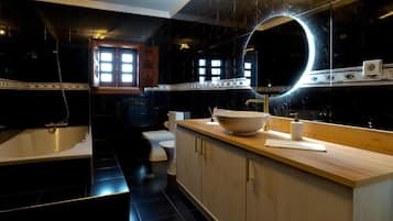 A modern bathroom with a freestanding bathtub, a large mirror with a circular light, and a wooden vanity.